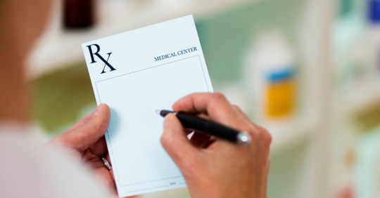 Medical doctor filling out a prescription on a prescription pad.