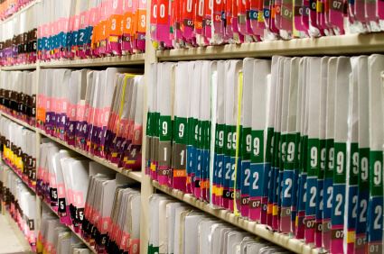 shelves of multi-colored numbered folders containing medical records 